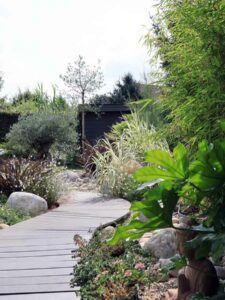 Chemin de jardin en bois traversant des massifs verdoyants et fleuris