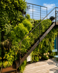 Escalier métallique entouré d’un mur végétal extérieur sur une terrasse contemporaine végétalisée.