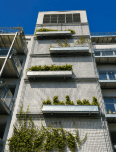 Façade d’immeuble moderne avec jardinières végétalisées et plantes grimpantes en milieu urbain.